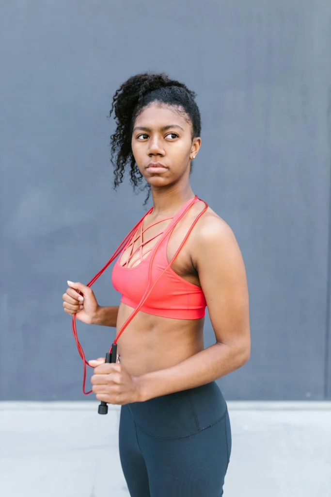 Image of a woman exercising with a resistance band, performing a stretching routine. She is in a well-lit room, wearing athletic clothing, and demonstrating proper form.